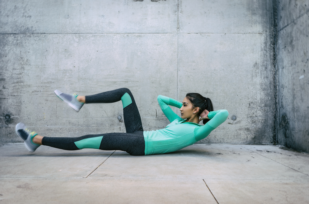 en kvinna använder sig av intensitetstekniker genom att göra liggande bencyklar på gymmet