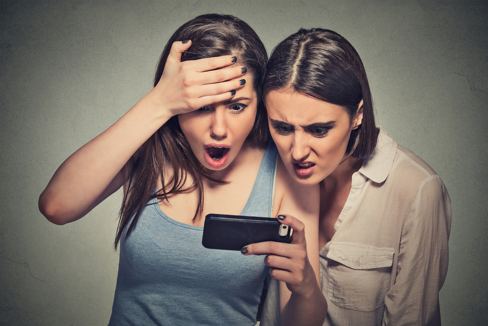 två kvinnor är chockade över vad de ser i en smartphone gällande resultat på gymmet