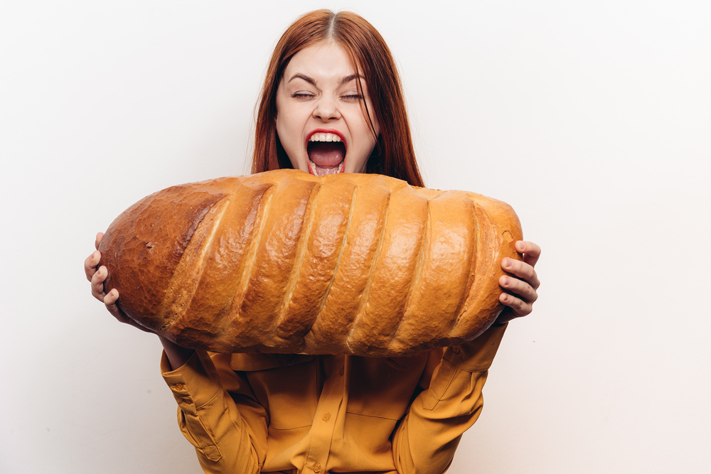en kvinna som ska ta en tugga av ett enormt stort bröd
