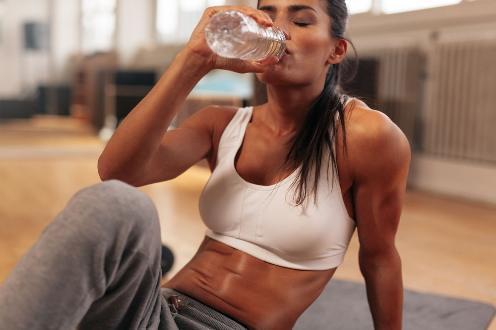 en tjej som dricker vatten för att påbörja sin återhämtning för att gå ner i vikt och bygga muskler med styrketräning