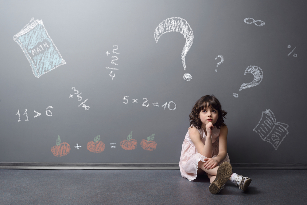 en liten flicka som sitter framför en svart tavla och funderar på matematiska uträkningar gällande hur tungt en man eller kvinna borde träna för sina resultat