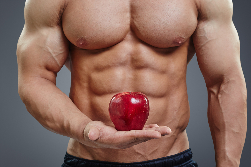en man som håller i ett rött äpple som dietmat