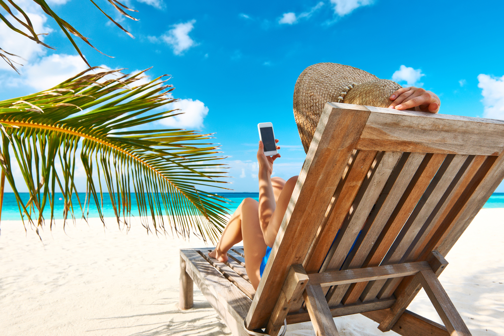 en kvinna som har sin pt online när hon är på semester på stranden